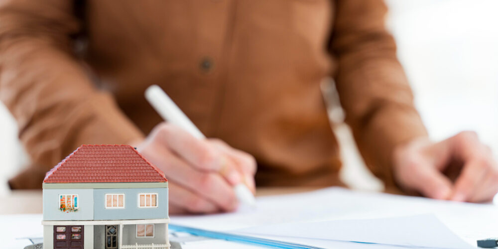 realtor-signing-contract-clipboard-miniature-house